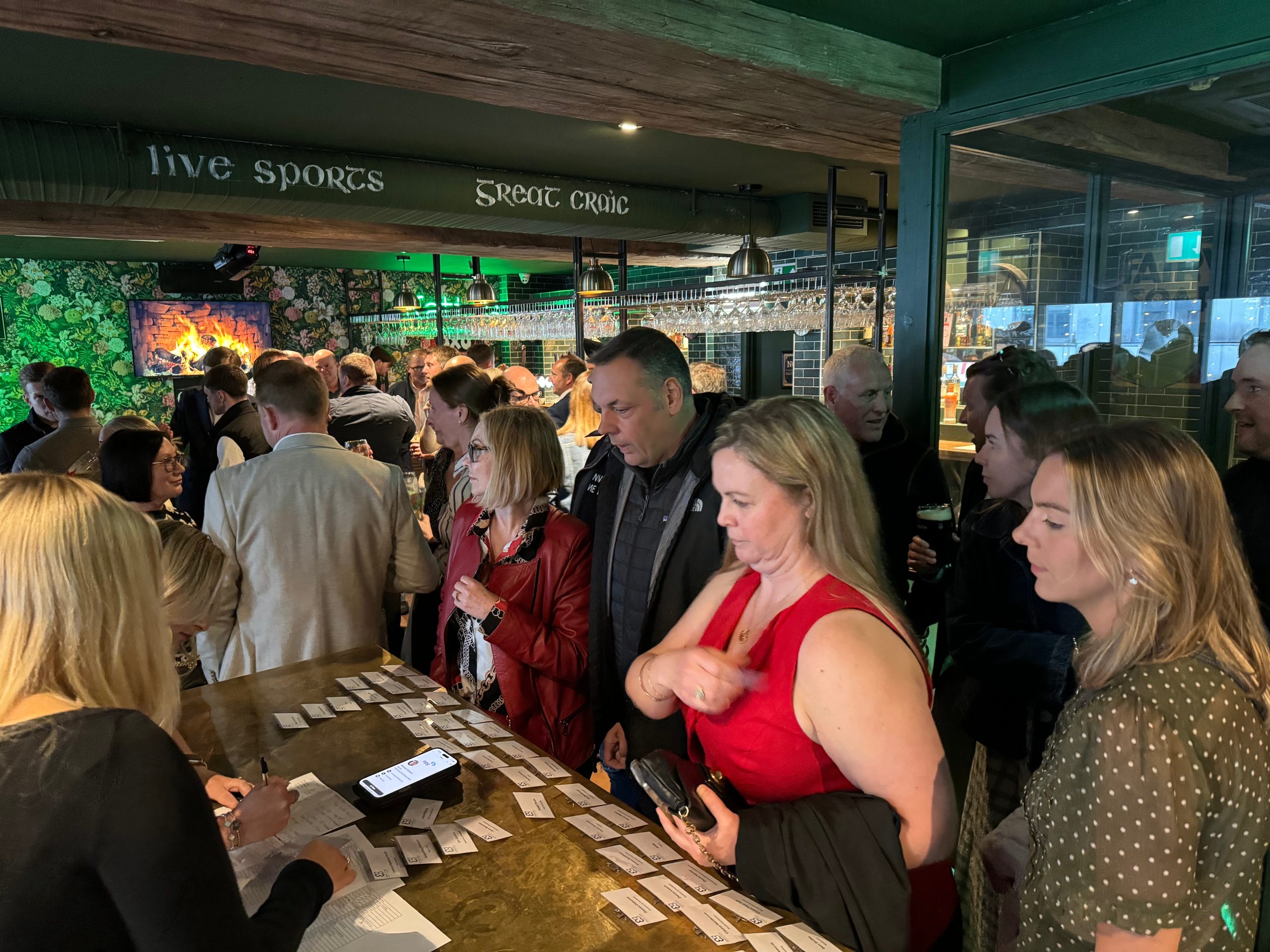 People gather at a busy bar for a Construction networking Leeds event, checking name badges.