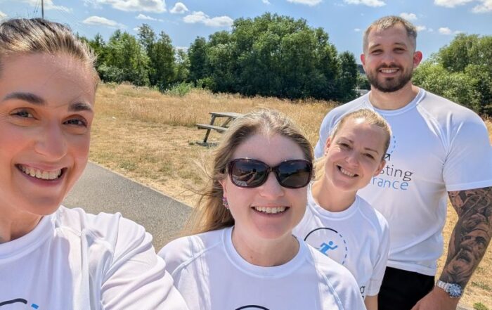 Four people in white shirts at a Construction networking Leeds event smile outdoors on a sunny day.