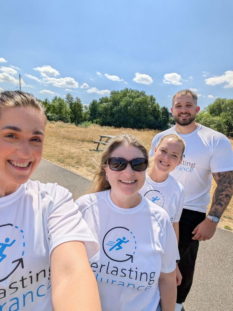 Four people in white shirts at a Construction networking Leeds event smile outdoors on a sunny day.
