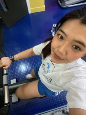 Woman in gym clothes on exercise bike, smiling—perfect for construction networking Leeds events.